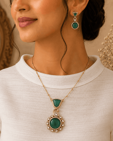 Emerald pendant necklace set with gold chain and matching drop earrings on model