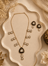 Black teardrop pendant necklace set with matching gold stud earrings and drop details