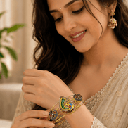 Woman wearing gold-tone cuff bracelet with green, blue, and gold enamel paisley motifs