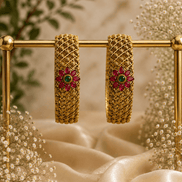 Pair of antique gold bangles with pink & green floral center stones, lattice hoop cuffs