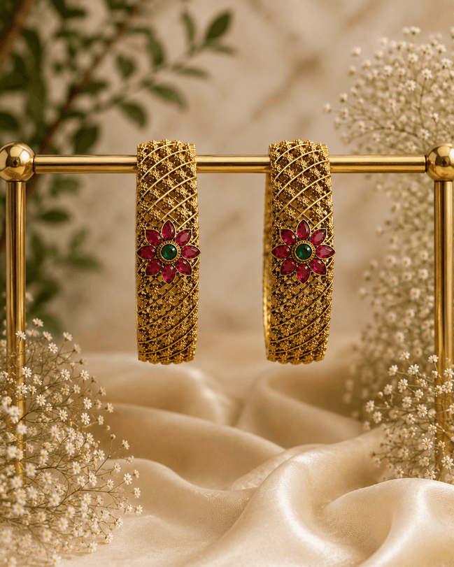 Pair of antique gold bangles with pink & green floral center stones, lattice hoop cuffs
