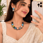 Multicolor stone necklace set with matching earrings, worn by a model in white