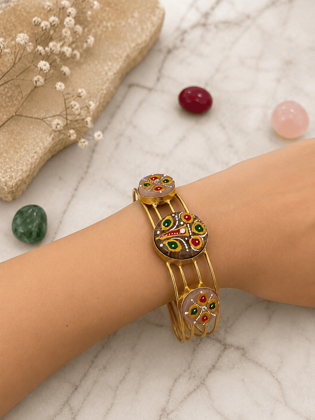 Enamel cuff bracelet with peacock center and round side charms on gold-tone band