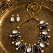 Mahira Heritage necklace set with black and white stones and pearls, shown with stud earrings.