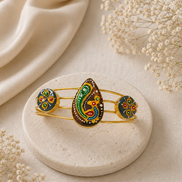 Gold-tone cuff bracelet with three colorful enamel motifs in green, blue, and gold