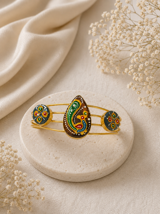 Gold-tone cuff bracelet with three colorful enamel motifs in green, blue, and gold