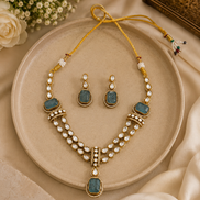 Gold kundan necklace and earrings set with peacock-blue teardrop stones and pearl drops