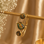 Gold-tone cuff bracelet with green multicolor enamel motif and two round black charms