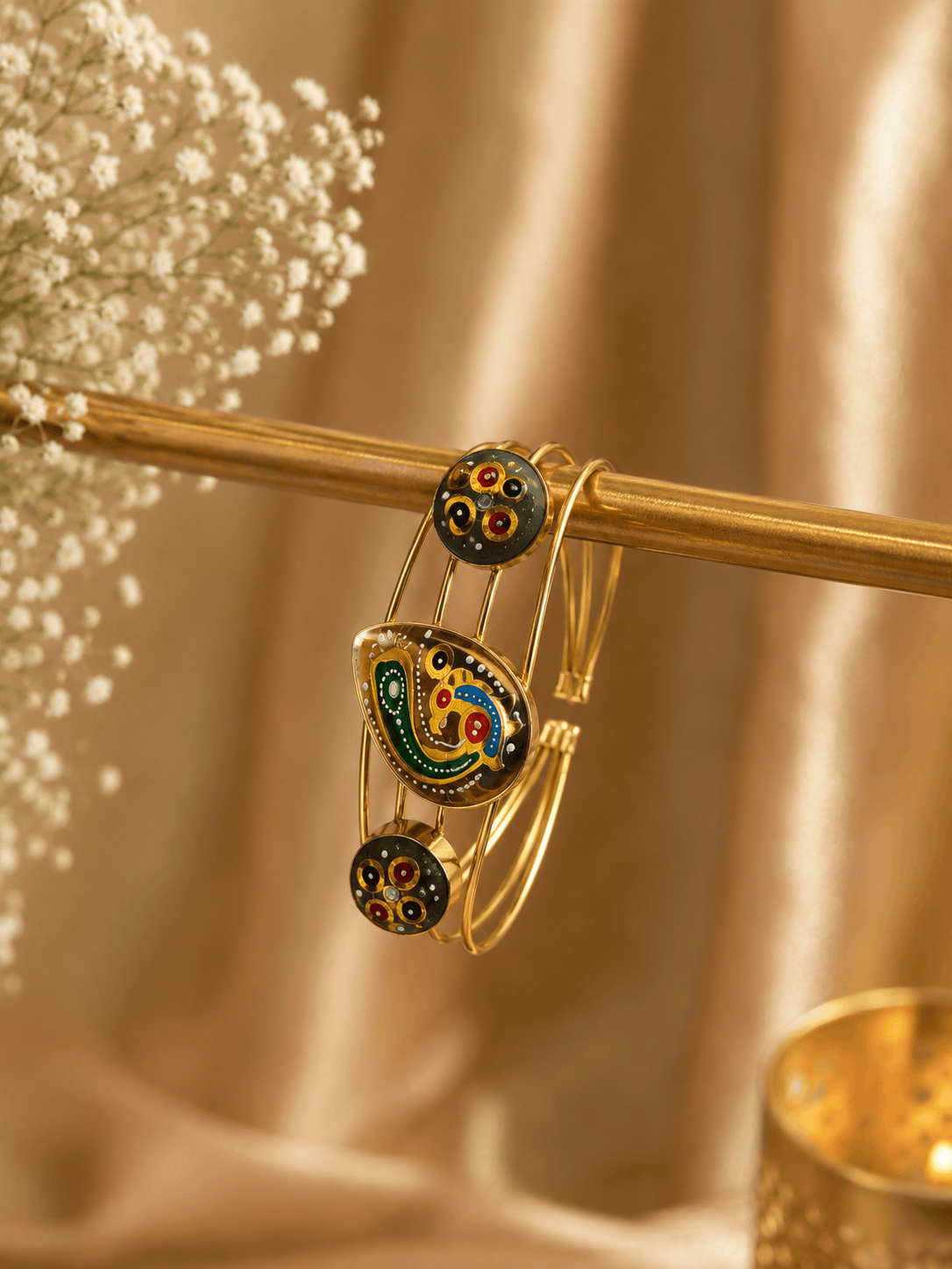 Gold-tone cuff bracelet with green multicolor enamel motif and two round black charms