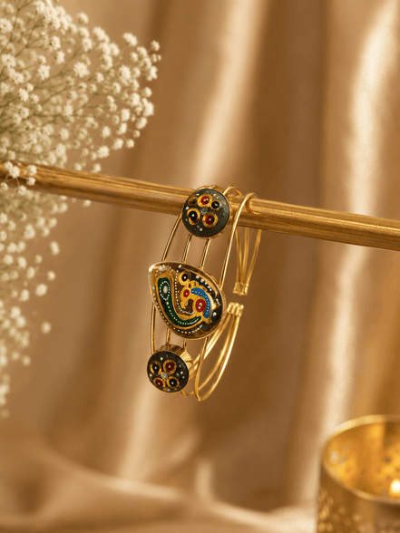 Gold-tone cuff bracelet with green multicolor enamel motif and two round black charms