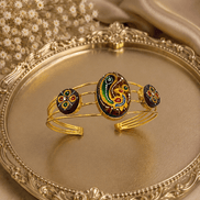 Gold-tone cuff bracelet with multicolor oval center and three round enamel accents