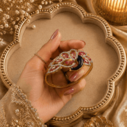 Gold kada with red, purple and black stone floral design, ornate border