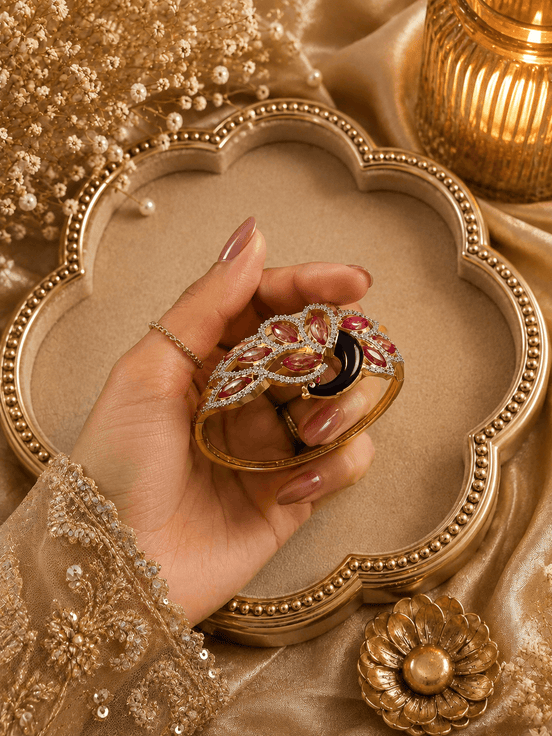 Gold kada with red, purple and black stone floral design, ornate border