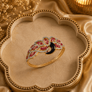 Ornate gold kada with red and purple stones and black center, curved band