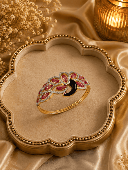 Ornate gold kada with red and purple stones and black center, curved band