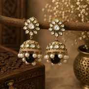 Gold-tone kundan jhumka earrings with green centers, pearl fringe, and blackish drops