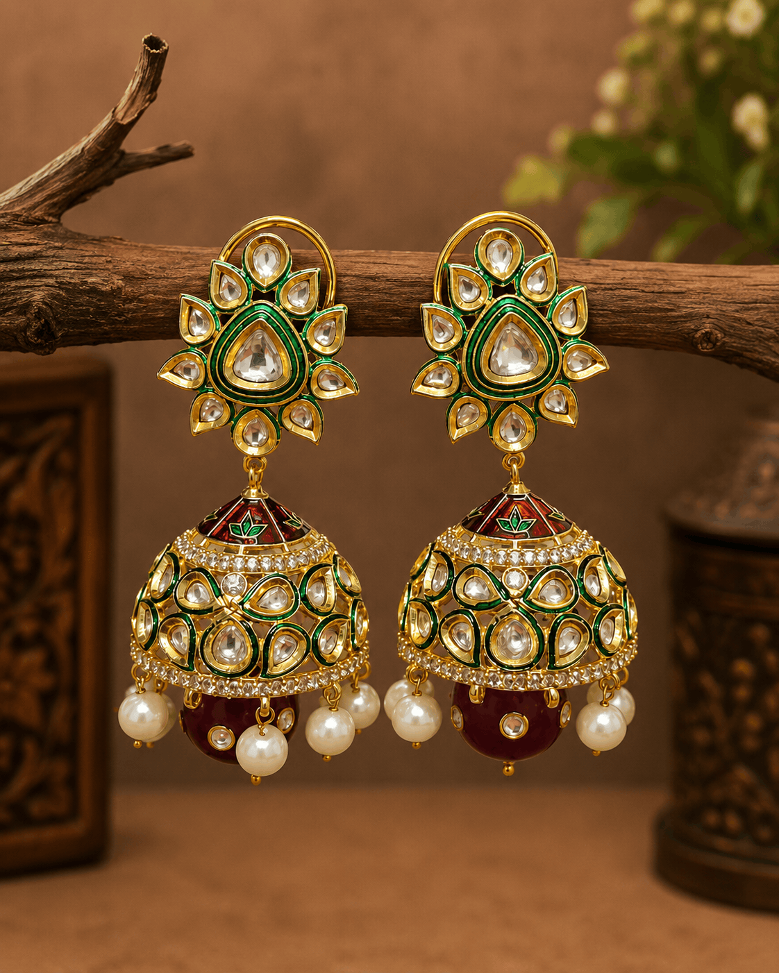 Gold-tone kundan jhumka earrings with green centers, pearl fringe, and dark red/green drops