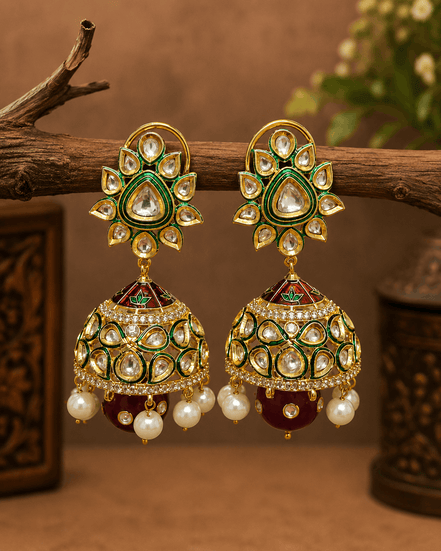 Gold-tone kundan jhumka earrings with green centers, pearl fringe, and dark red/green drops