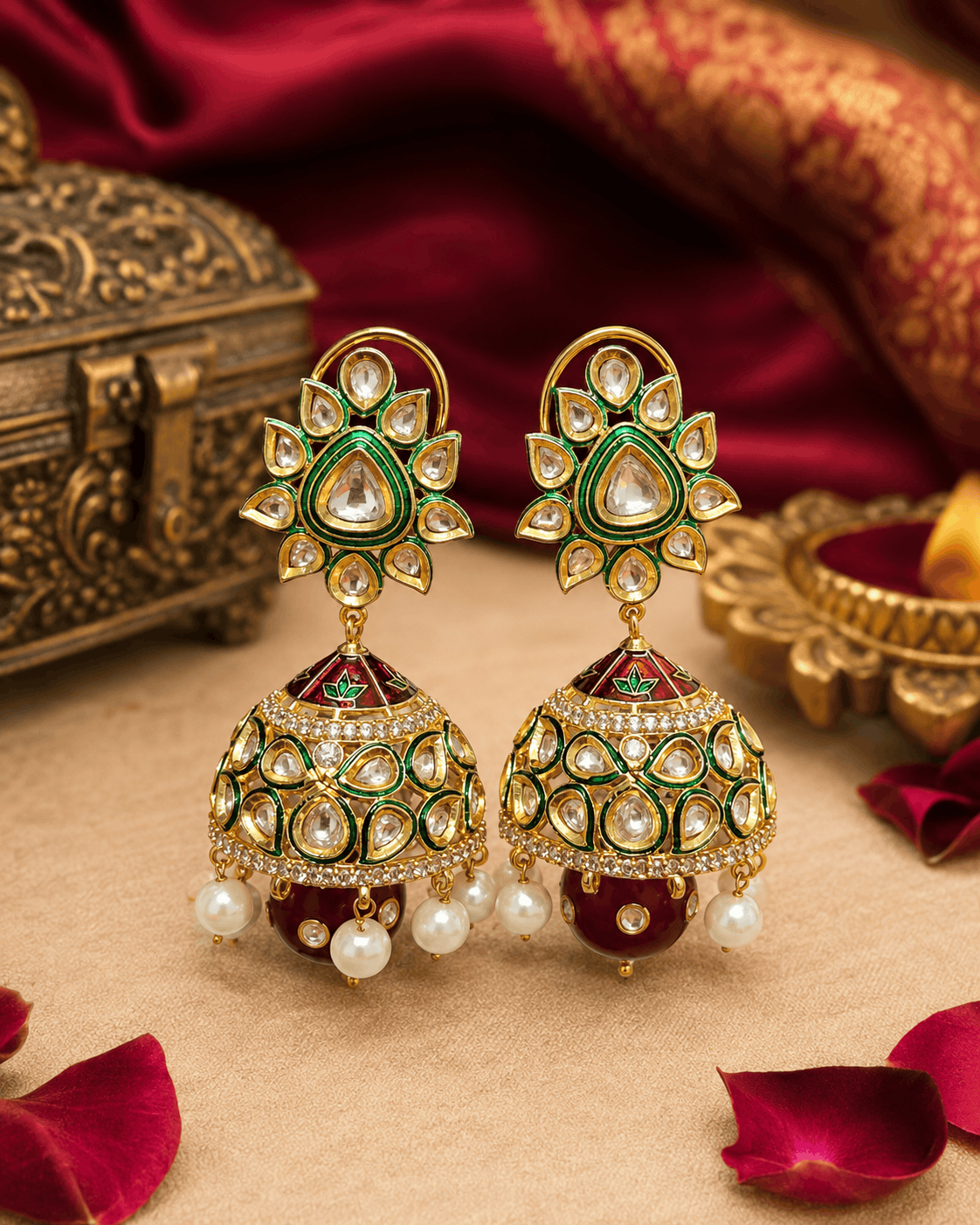 Gold-tone kundan jhumka earrings with green centers, enamel dome, and pearl fringe
