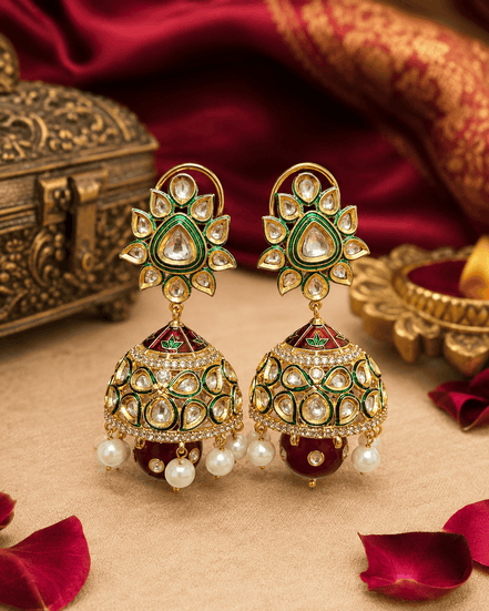 Gold-tone kundan jhumka earrings with green centers, enamel dome, and pearl fringe