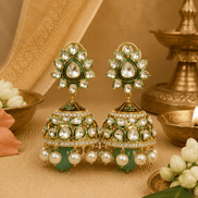 Gold-tone kundan jhumka earrings with green centers and pearl fringe, teal drops