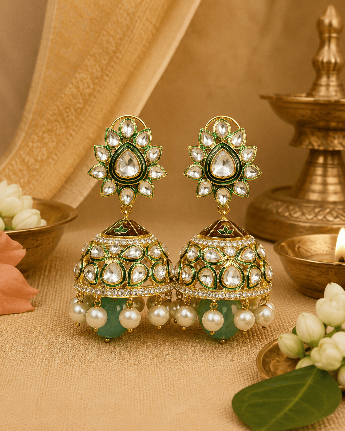 Gold-tone kundan jhumka earrings with green centers and pearl fringe, teal drops