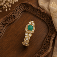 Gold tone Kada bracelet with oval emerald centerpiece and round pearl stones
