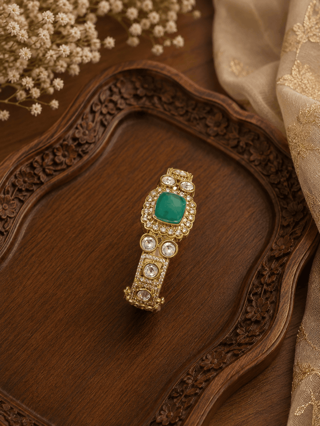 Gold tone Kada bracelet with oval emerald centerpiece and round pearl stones
