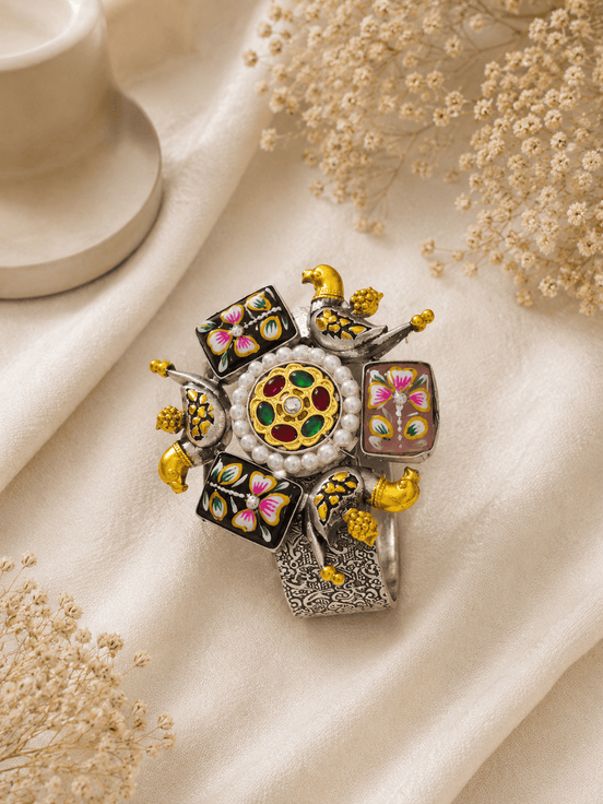 Ornate floral cuff bracelet with gold beads, colorful enamel squares, and jeweled center