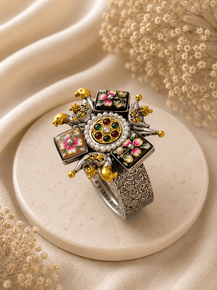 Wide silver-tone cuff with round jeweled center, enamel flower panels, and gold accents