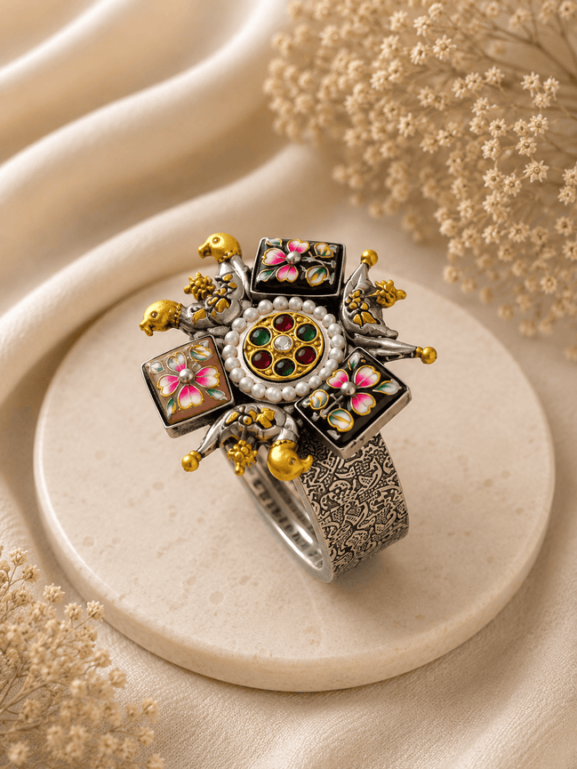Wide silver-tone cuff with round jeweled center, enamel flower panels, and gold accents