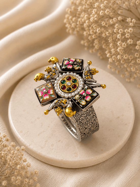 Wide silver-tone cuff with round jeweled center, enamel flower panels, and gold accents