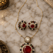Gold-tone necklace and round stud earrings with red and green center stones, blue accents