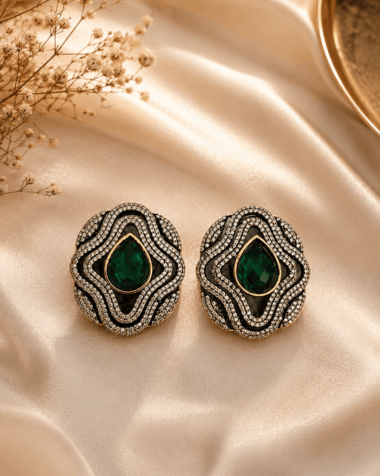 Brass-tone statement stud earrings with green teardrop center and crystal surround