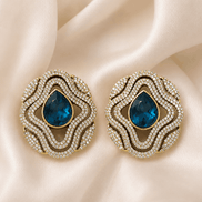 Brass-tone statement stud earrings with blue teardrop center and layered crystal trim