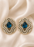 Brass-tone statement stud earrings with blue teardrop center and layered crystal trim