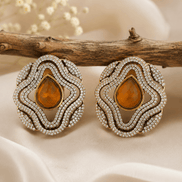 Brass-tone statement stud earrings with amber teardrop center and crystal halo border