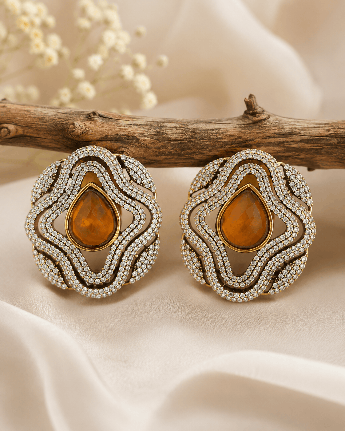 Brass-tone statement stud earrings with amber teardrop center and crystal halo border