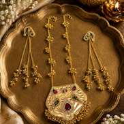 Gold-tone necklace with kundan pendant and matching drop earrings on decorative tray