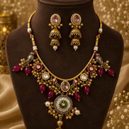 Gold-tone necklace and earrings set with pink oval center and green stone accents on dark bust