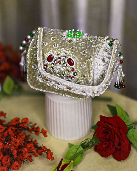 Beige jeweled box clutch with ornate front frame, pearl-like bead fringe, short handle