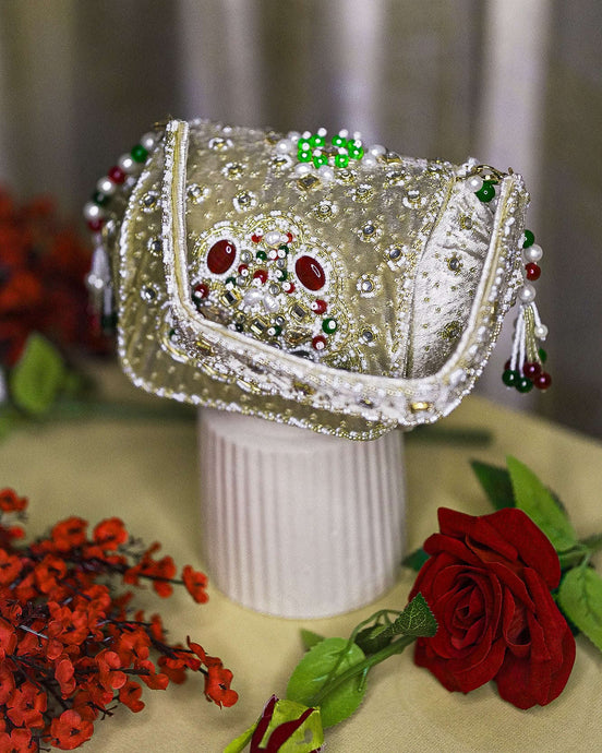 Beige jeweled box clutch with ornate front frame, pearl-like bead fringe, short handle