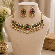 Gold-tone kundan necklace set with dark green center stones and dangling earrings.