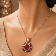 Gold-tone pendant necklace and round stud earrings with pink center stones and blue accents