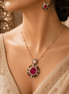 Gold-tone pendant necklace and round stud earrings with pink center stones and blue accents