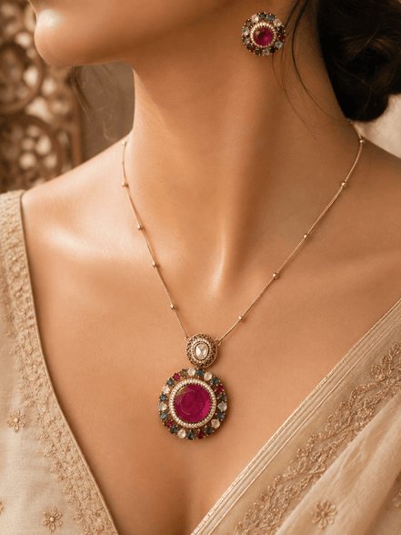Gold-tone pendant necklace and round stud earrings with pink center stones and blue accents
