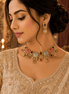 Woman wearing gold-tone gemstone necklace with matching stud earrings and drop charms