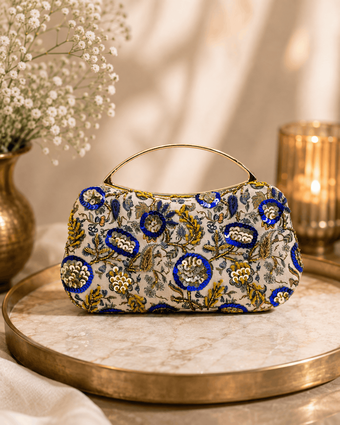 Beige floral clutch bag with blue and gold ornaments and curved top handle