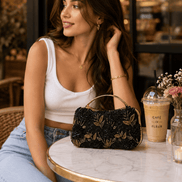 Black floral clutch bag with gold embroidered flowers, styled on table
