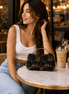 Black floral clutch bag with gold embroidered flowers, styled on table